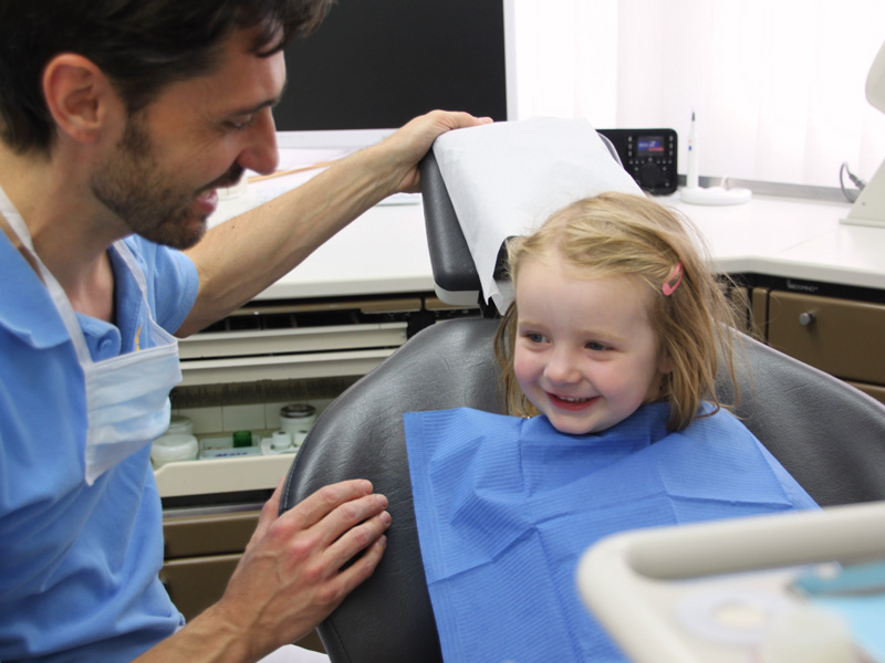 Das Bild zeigt einen Zahnarzt bei der Behandlung eines Kindes